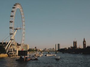 Dusk view of the London Eye and Big Ben along the River Thames, capturing iconic London cityscape.